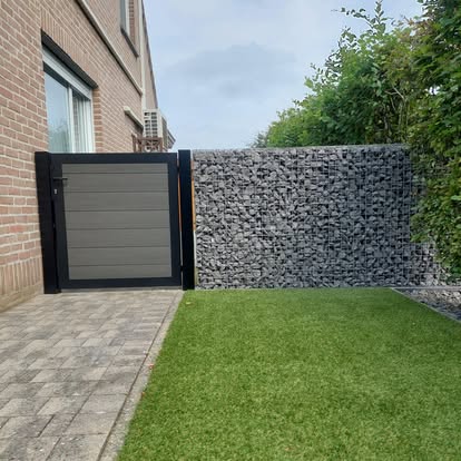 Antracieten tuinpoort met composietvulling naast een schanskorfmuur